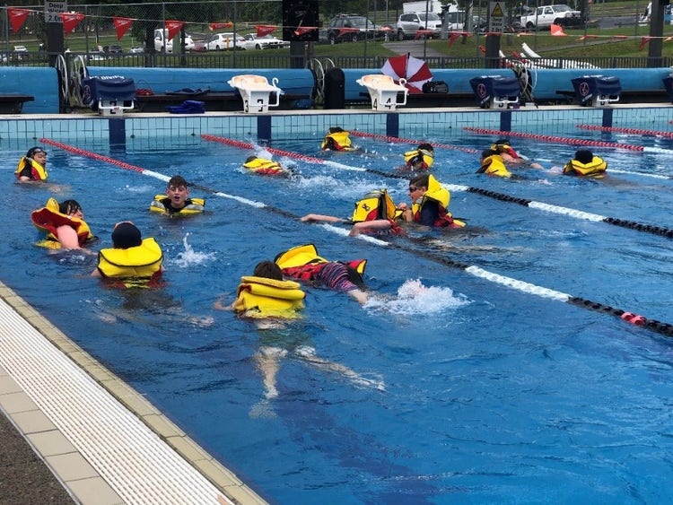 students swimming in the pool with life jackets